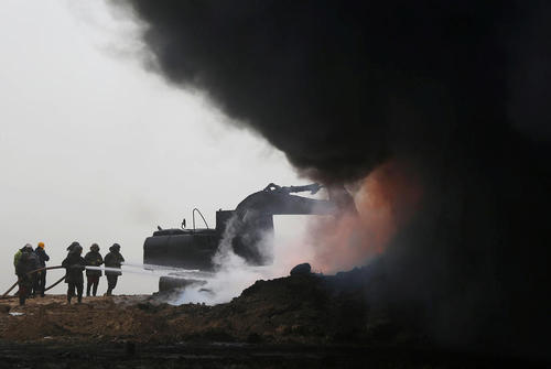 تلاش آتش نشانان عراقی برای خاموش کردن آتش چاه های نفتی حومه شهر موصل که از سوی داعش به آتش کشیده شده اند