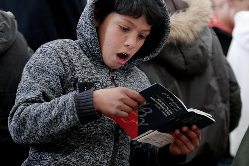 کودک پناهجو در اردوگاهی در شهر آتن یونان مشغول مطالعه جزوه آموزش زبان که از سوی وزارت مهاجرت یونان برای تسهیل ارتباطات با مهاجران داده شده است. این جزوه به 6 زبان است از جمله عربی، اردو، فارسی و فرانسوی